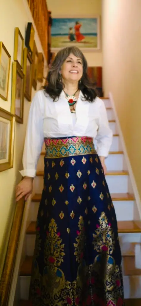 Kristina on a staircase in a white shirt and an embroidered navy skirt