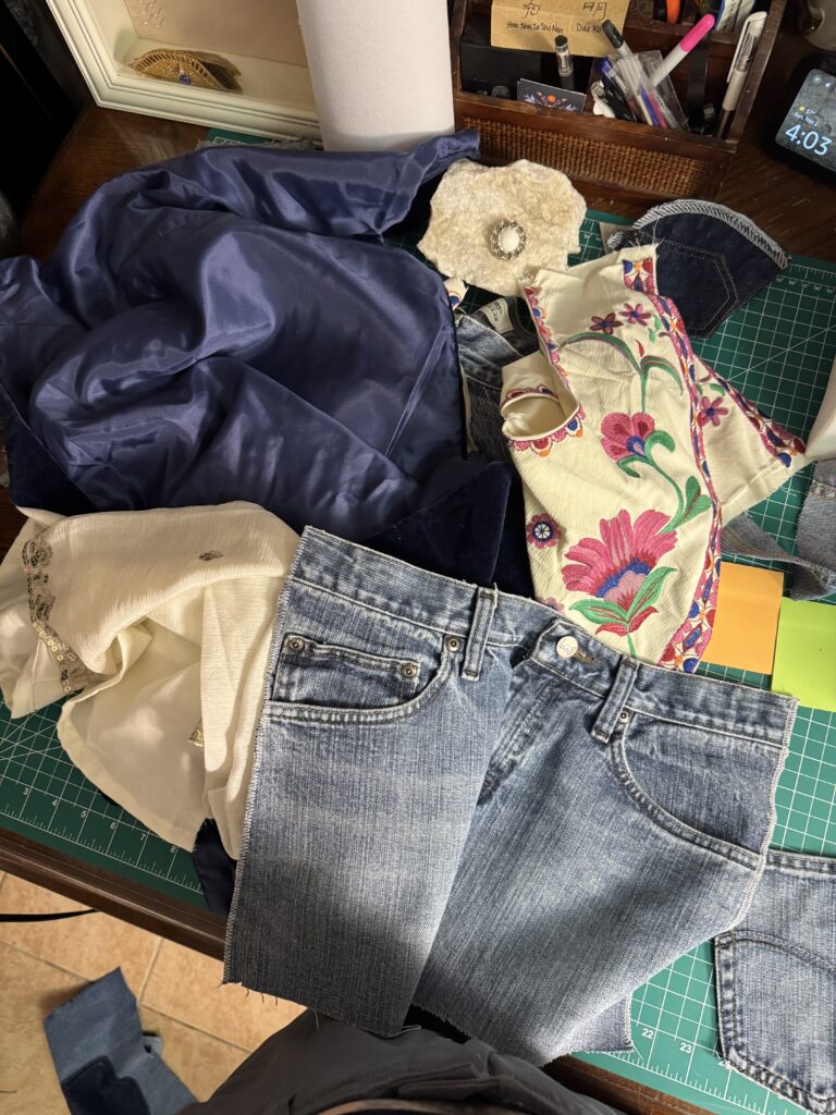Upcycled denim fabric and embroidered materials laid out on a cutting mat at The Gracewell Studio workspace